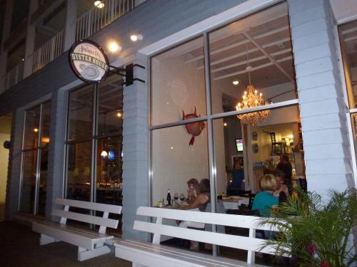 Exterior of an oyster house with large windows, showcasing diners inside and a decorative chandelier.