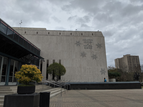 Exterior view of the Houston Museum of Natural Science, featuring a modern building and cloudy sky.