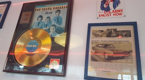 Gold record of The Young Rascals on the wall, alongside a vintage Dodge Charger advertisement.