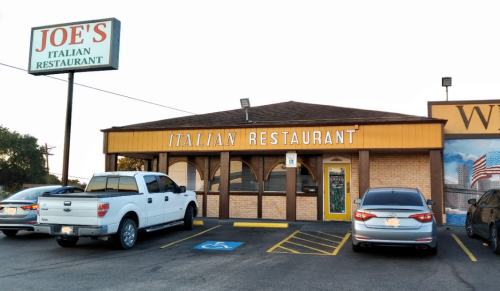 A brick building with a sign reading "Joe's Italian Restaurant" and parked cars in front.