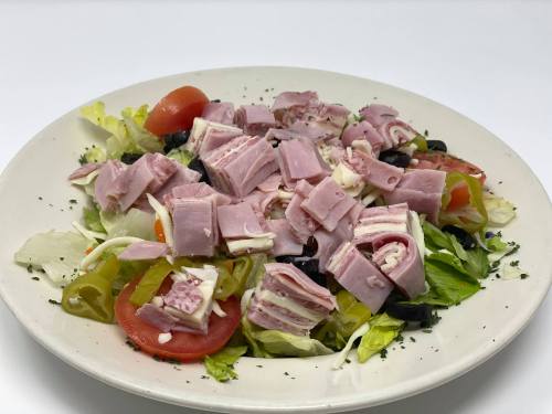 A colorful salad topped with diced ham, lettuce, tomatoes, and peppers on a white plate.