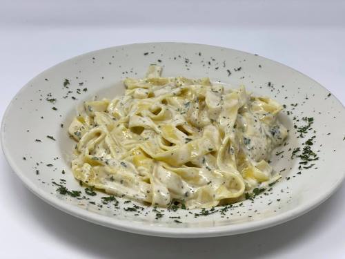 A plate of fettuccine pasta in a creamy sauce, garnished with herbs on a white background.