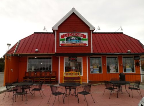 Exterior of La Cascada restaurant with a red roof, orange walls, and outdoor seating area. Sign reads "Authentic Mexican Food."