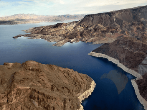 Aerial view of a rugged landscape with mountains and a blue lake, showcasing rocky shores and varied terrain.