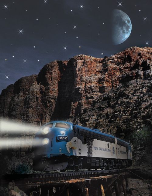 A blue train travels through a mountainous landscape under a starry sky and a large moon.