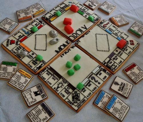 A colorful Monopoly-themed cookie set, featuring game board, properties, and tokens made of decorated cookies.