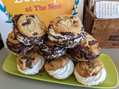 A colorful plate stacked with cookie sandwiches filled with cream and topped with chocolate sprinkles.