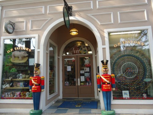 Entrance of O.P. Taylor's toy store, featuring colorful displays and nutcracker figures on either side of the door.