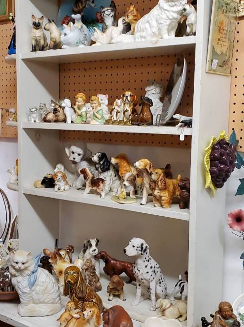 A display shelf filled with various ceramic animal figurines, including dogs, cats, and children.