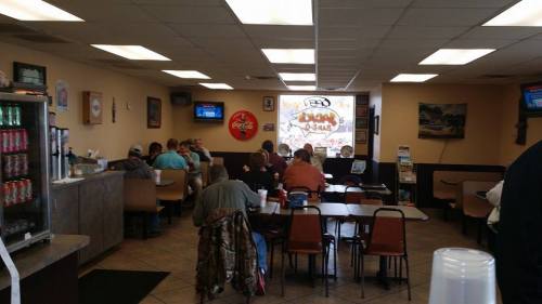 A casual diner interior with patrons seated at tables, a soda fountain, and a large window displaying a mural.