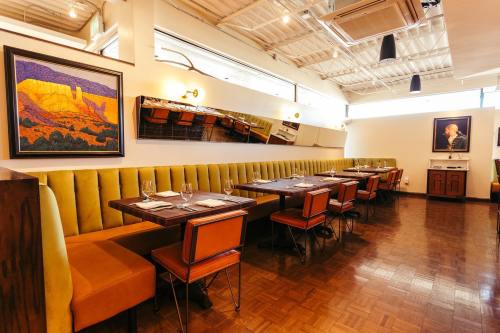 Interior of a modern restaurant featuring yellow booths, wooden accents, and artwork on the walls.
