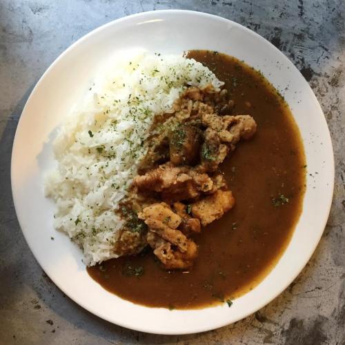 A plate of rice served with chicken in a brown sauce, garnished with herbs.