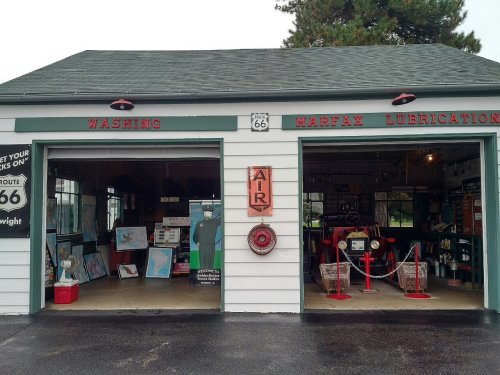 A vintage garage with two bays labeled "WASHING" and "MARFAX LUBRICATION," featuring Route 66 memorabilia inside.