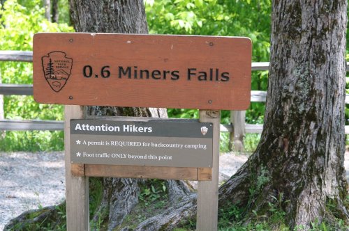 Signpost indicating 0.6 miles to Miners Falls, with notes on camping permits and foot traffic restrictions.