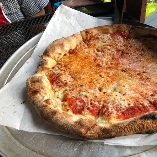A freshly baked pizza with a golden crust and melted cheese, served on a round plate.