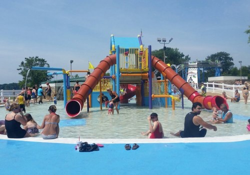 A vibrant water park with colorful slides, children playing in the water, and families enjoying the sunny day.