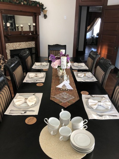 Elegant dining table set with white dishes, floral centerpieces, and decorative napkins in a warm, inviting room.