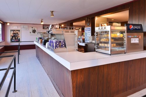 Interior of a concession stand with a counter, display cases, and various snacks, featuring a Pepsi sign.
