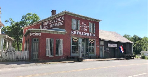 Historic red brick building with "R.H. Wilson & Son" signage, featuring a post office and an antique shop.
