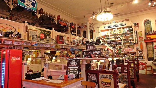 A nostalgic diner interior filled with vintage signs, memorabilia, and retro decor, creating a lively atmosphere.