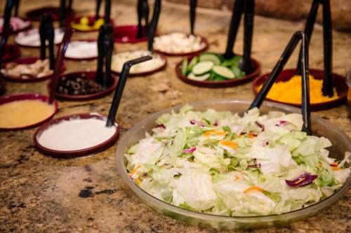 A bowl of fresh salad with various toppings and dressings in the background on a granite countertop.