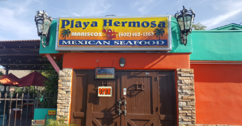 Colorful exterior of "Playa Hermosa" Mexican seafood restaurant with an open sign and palm tree decorations.