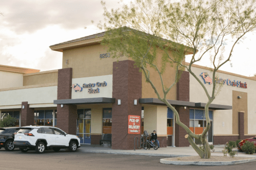 Exterior of a restaurant named "Angry Crab Shack," featuring a parking lot and a tree in front.