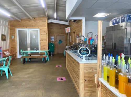 Interior of a cozy café with wooden walls, colorful seating, and a counter displaying various drinks and syrups.