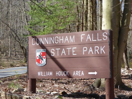 Sign for Cunningham Falls State Park, featuring the park's name and a directional arrow to the William Houck Area.