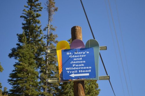 Signpost for St. Mary's Glacier and James Peak Wilderness Trail Head, with colorful directional arrows against a blue sky.