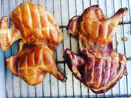Two beautifully roasted chickens on a wire rack, showcasing golden-brown skin and crispy texture.