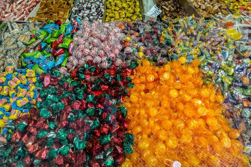 A colorful assortment of candies in various shapes and wrappers, including reds, greens, oranges, and purples.