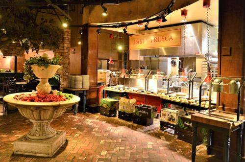 A cozy restaurant interior featuring a pasta station, fresh produce, and a decorative fountain. Warm lighting enhances the ambiance.