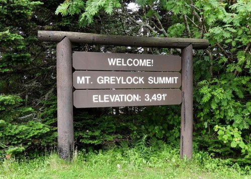 Welcome sign at Mt. Greylock Summit, displaying an elevation of 3,491 feet, surrounded by greenery.