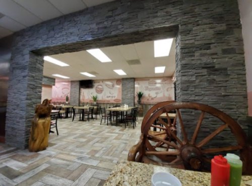 Interior of a restaurant featuring stone walls, wooden accents, and tables with chairs, creating a cozy atmosphere.