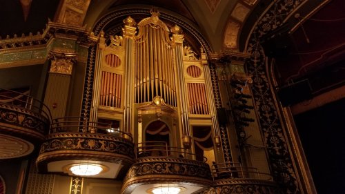 Ornate theater interior featuring a grand pipe organ and decorative balconies.