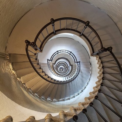A spiral staircase viewed from above, showcasing a series of circular steps and railings.