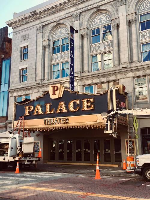 Exterior of the Palace Theater, featuring a marquee and classic architecture, with construction vehicles nearby.