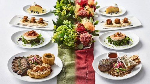A beautifully arranged table featuring gourmet dishes, a floral centerpiece, and dessert plates.
