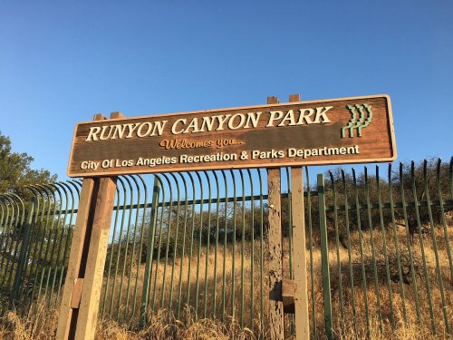 Sign for Runyon Canyon Park, welcoming visitors, with a clear blue sky in the background.
