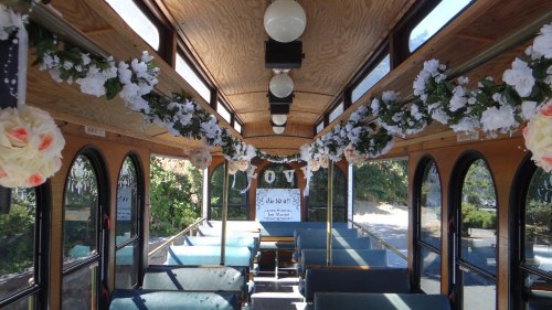 Interior of a decorated trolley with floral arrangements and seating, creating a festive atmosphere.
