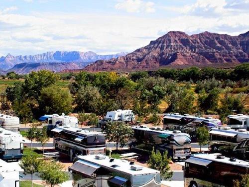 A scenic view of an RV park with mountains in the background and lush greenery surrounding the vehicles.