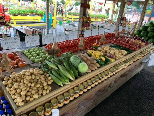 A vibrant market display featuring various fresh vegetables and fruits, including potatoes, corn, and tomatoes.
