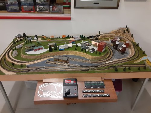 A model train layout featuring tracks, buildings, and scenery on a tabletop display.