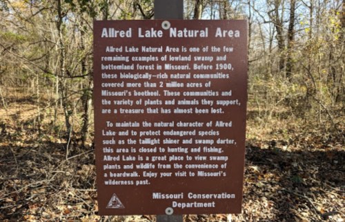 Sign for Allred Lake Natural Area, highlighting its unique swamp and forest ecosystem in Missouri. Conservation message included.