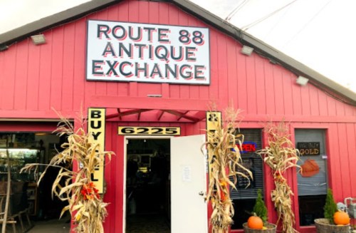 A red building with a sign reading "Route 88 Antique Exchange," featuring corn stalks and pumpkins at the entrance.