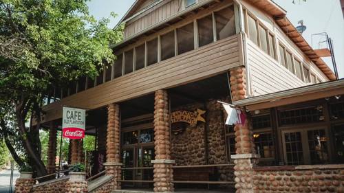 A rustic building with stone columns and a sign for a café, surrounded by trees and featuring a Coca-Cola logo.