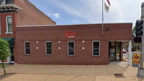 Exterior view of Gus's restaurant, featuring a brick facade and a sign, with a flag and traffic light nearby.