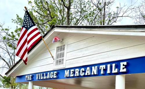Sign for "The Village Mercantile" with an American flag displayed on the building.