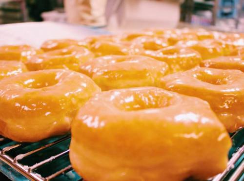 Freshly glazed donuts cooling on a wire rack, glistening with a shiny, sweet glaze.